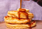 Side view of pouring syrup on pancakes