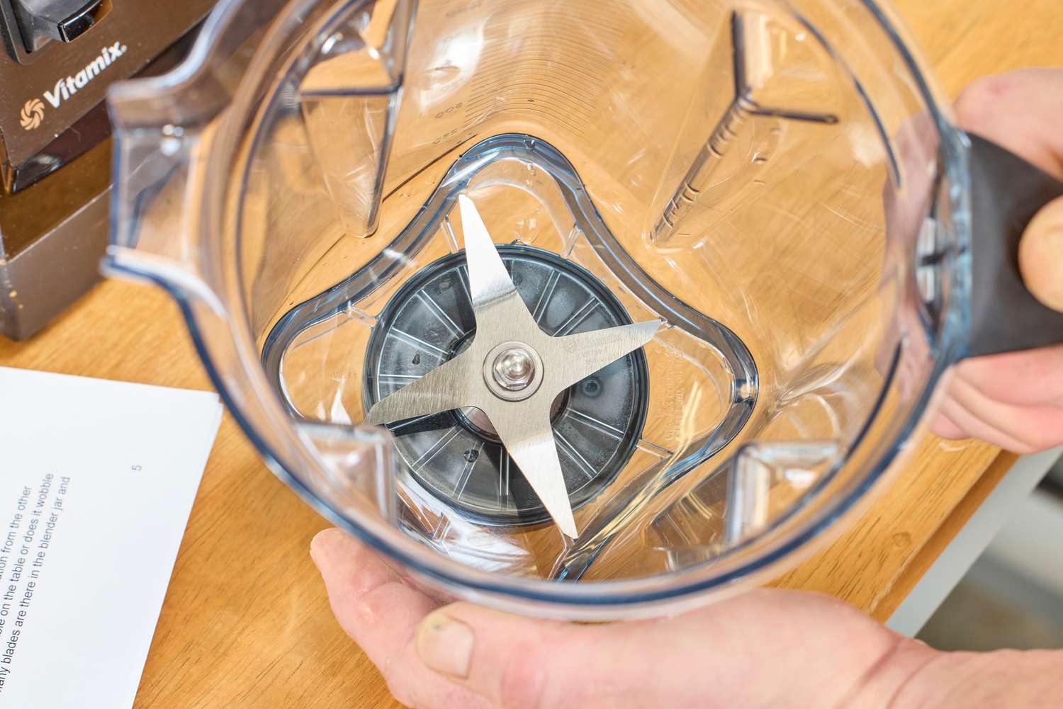 An overhead view of two hands holding an empty Vitamix 7500