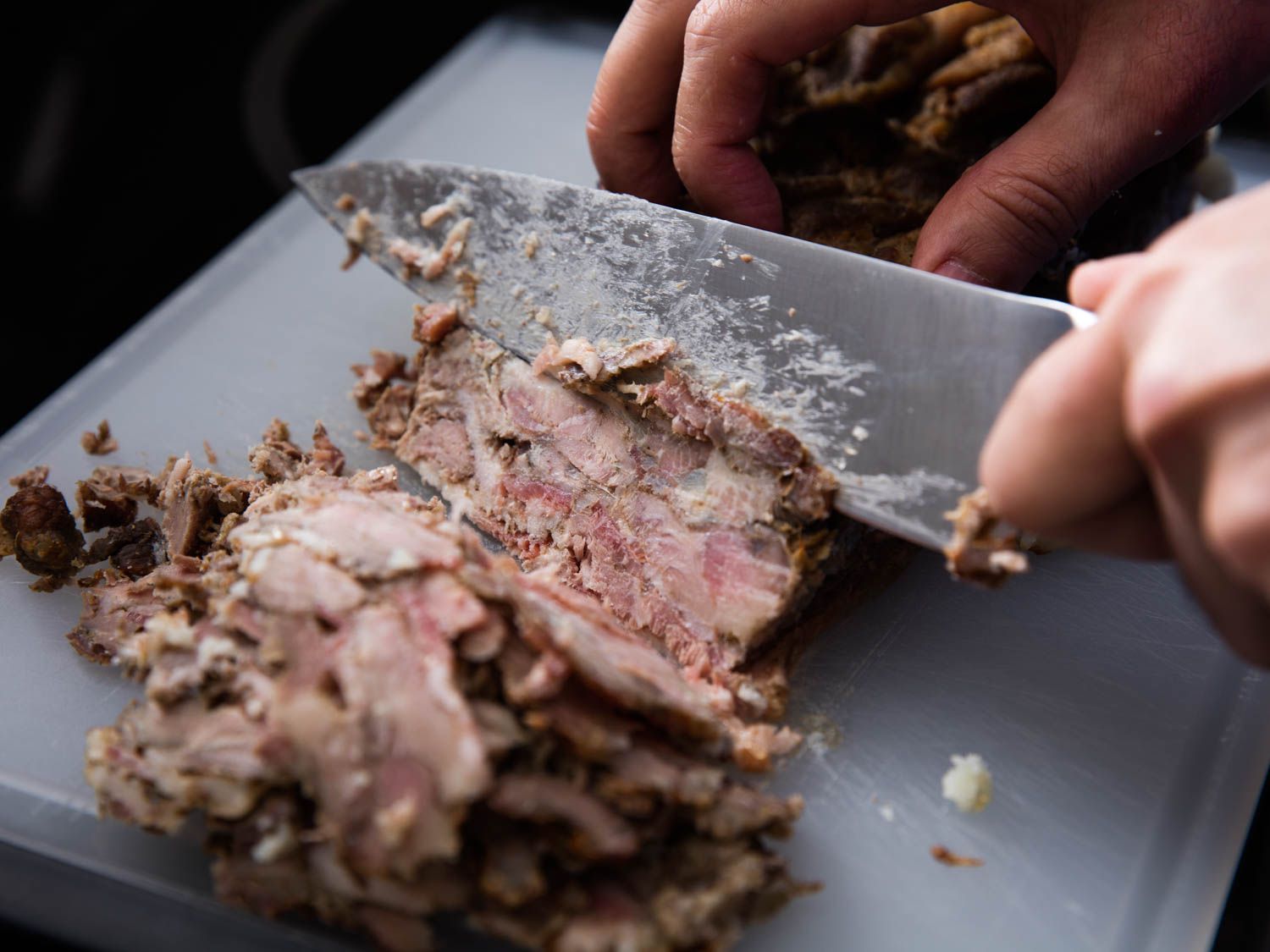 The cooked pork-bacon-onion loaf is thinly sliced with a chef's knife.