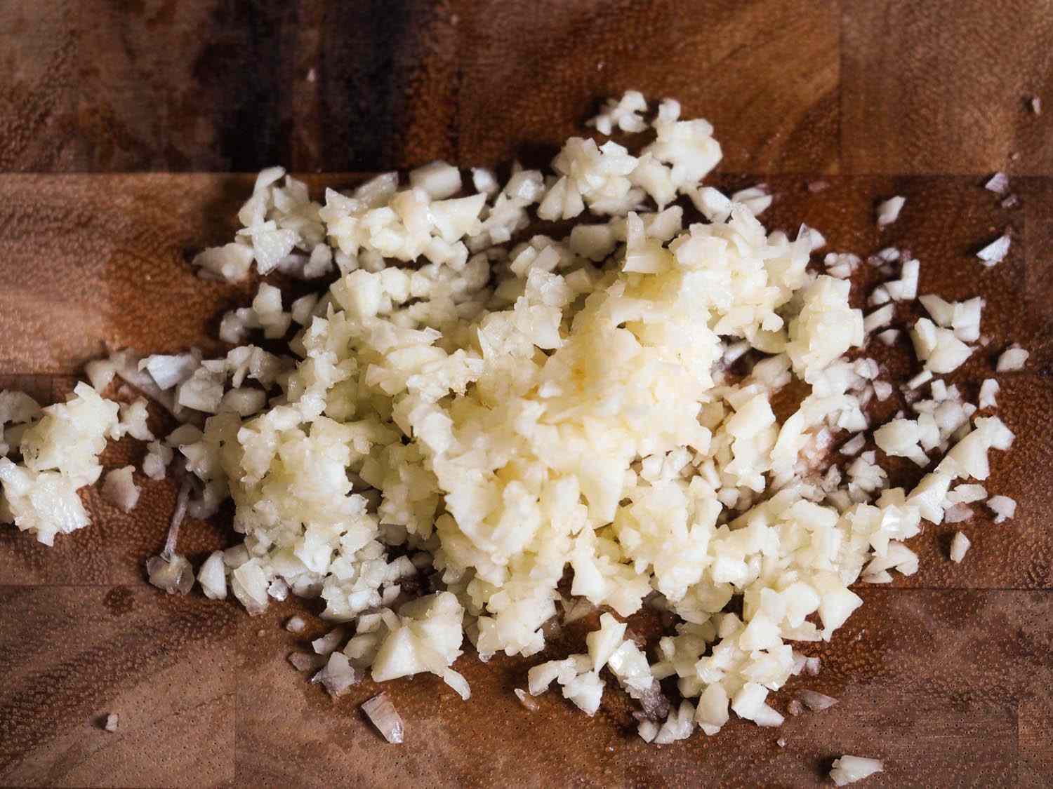 Closeup of finely chopped garlic on a wooden cutting board.