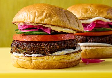 Falafel burgers with tomato cucumber pickled onions and spread on buns displayed on a table