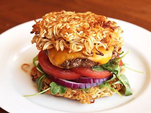 Cheeseburger with baby greens and sliced tomato and red onion, sandwiched between two pan-fried ramen "buns" 