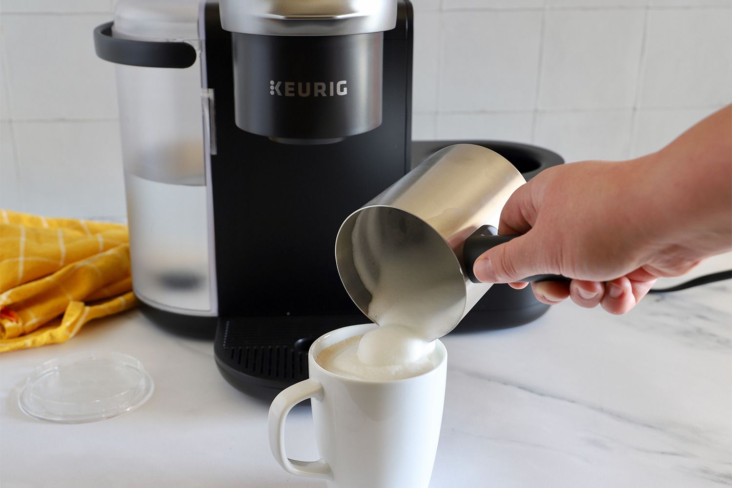 Milk foam being poured on top of coffee into a mug.
