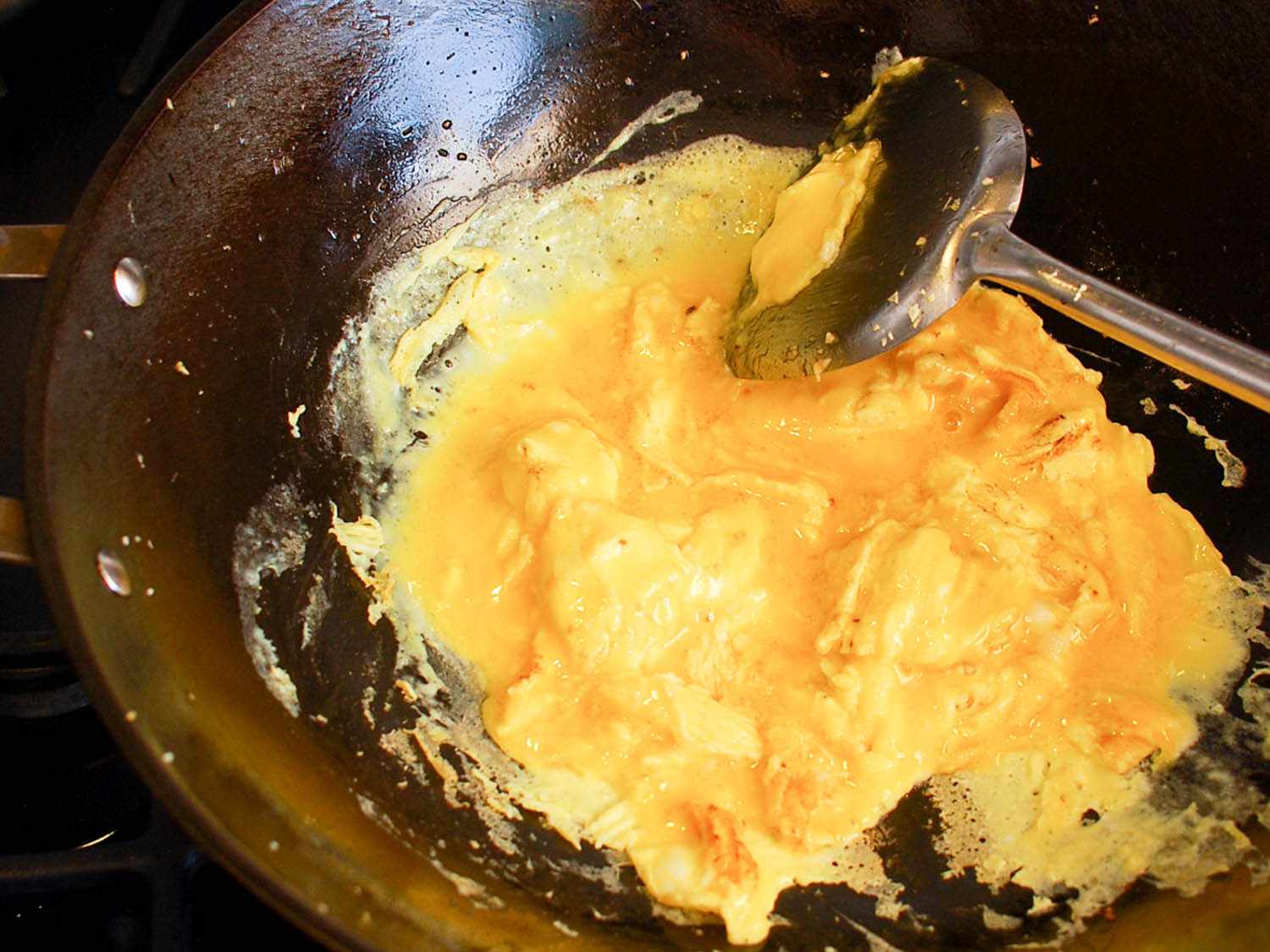 Beaten egg being scrambled in a wok.