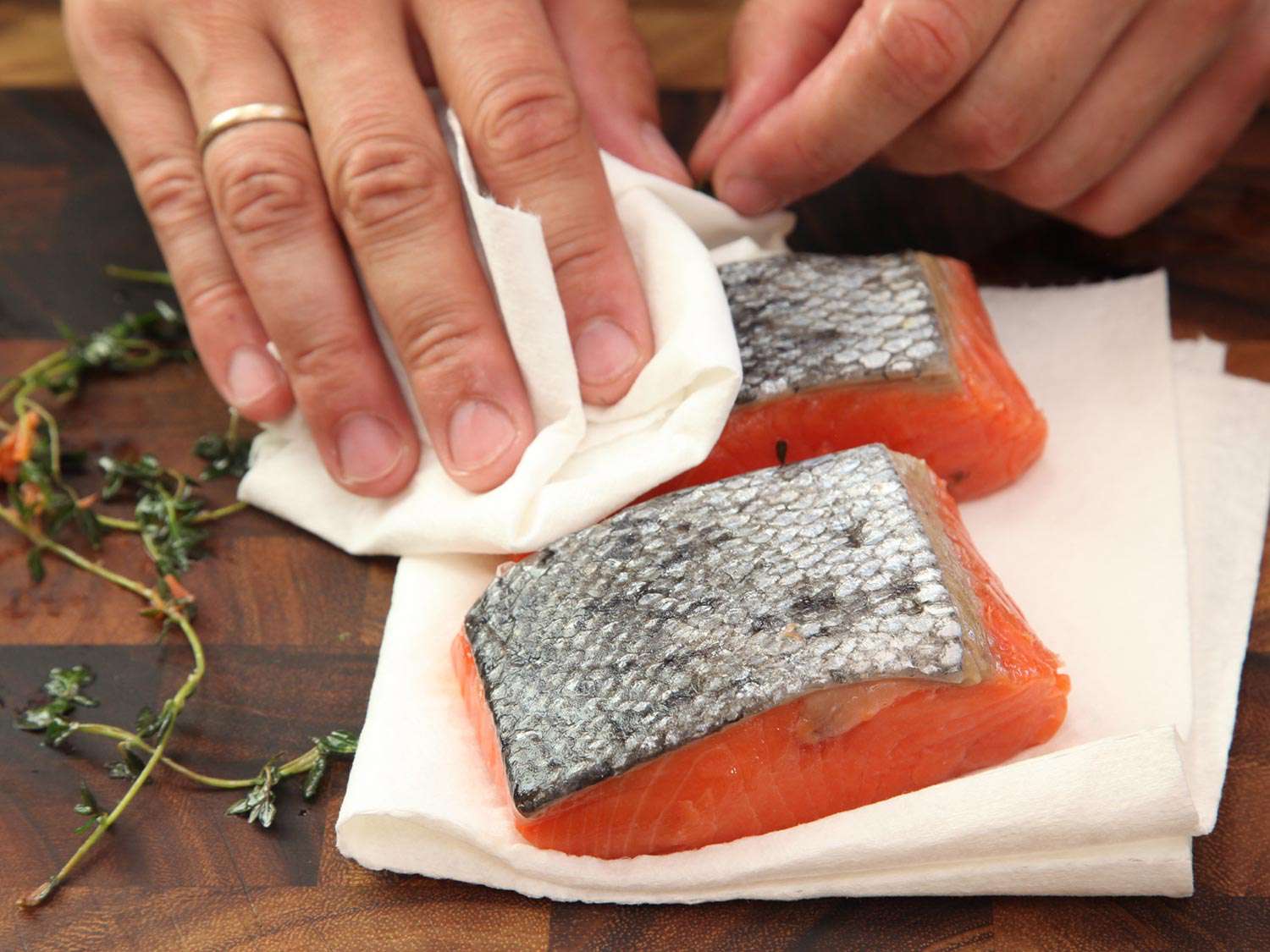 Carefully blotting salmon fillets dry with paper towels after cooking sous vide.