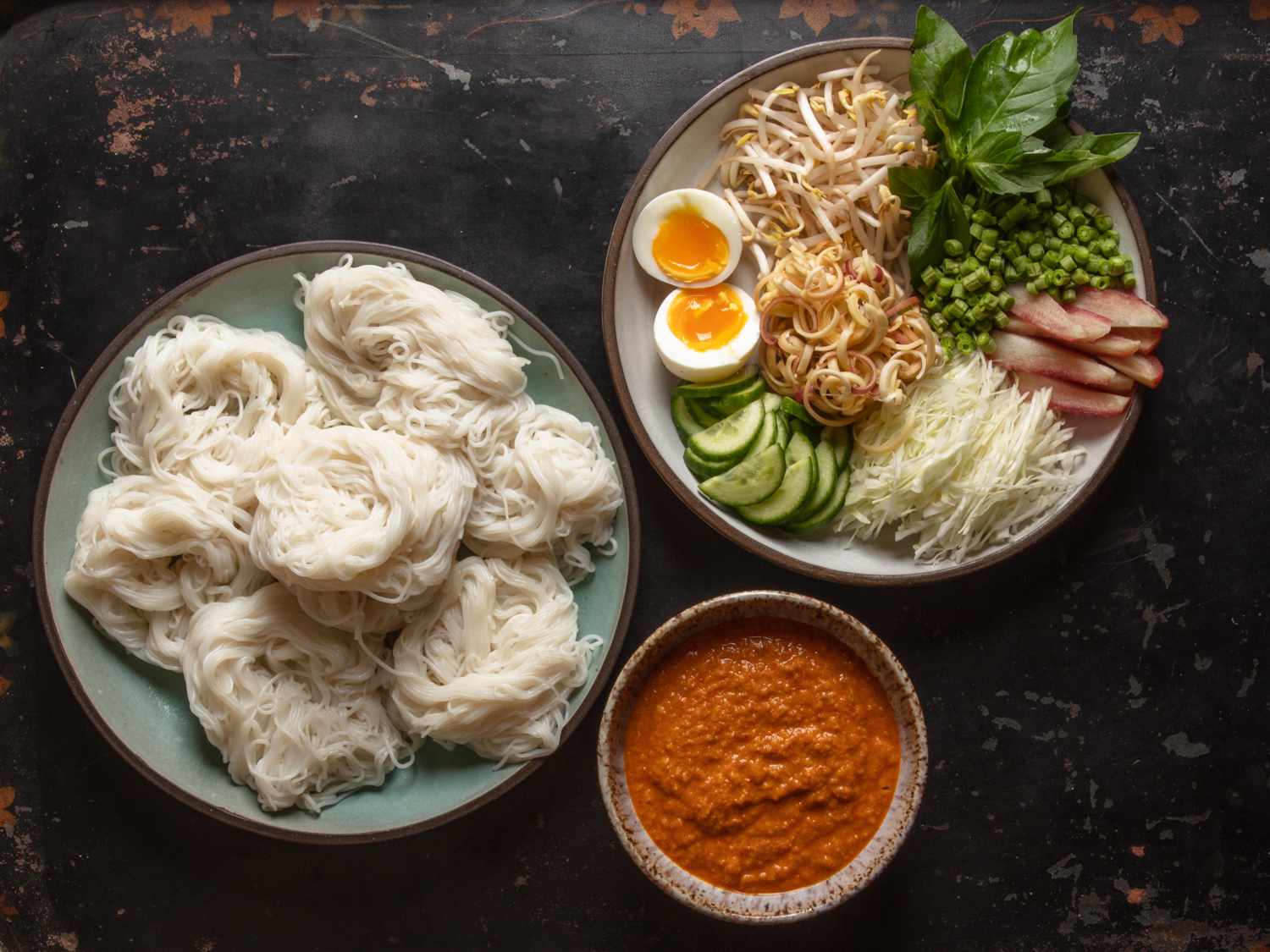 Overhead of serving dishes of noodles, vegetables, and fish curry