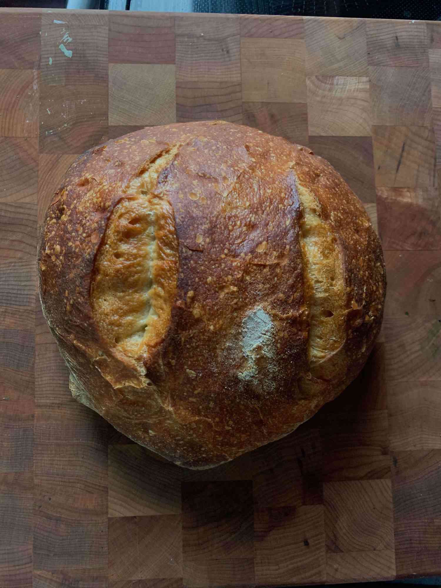 overhead view of boule of white bread on a cutting board