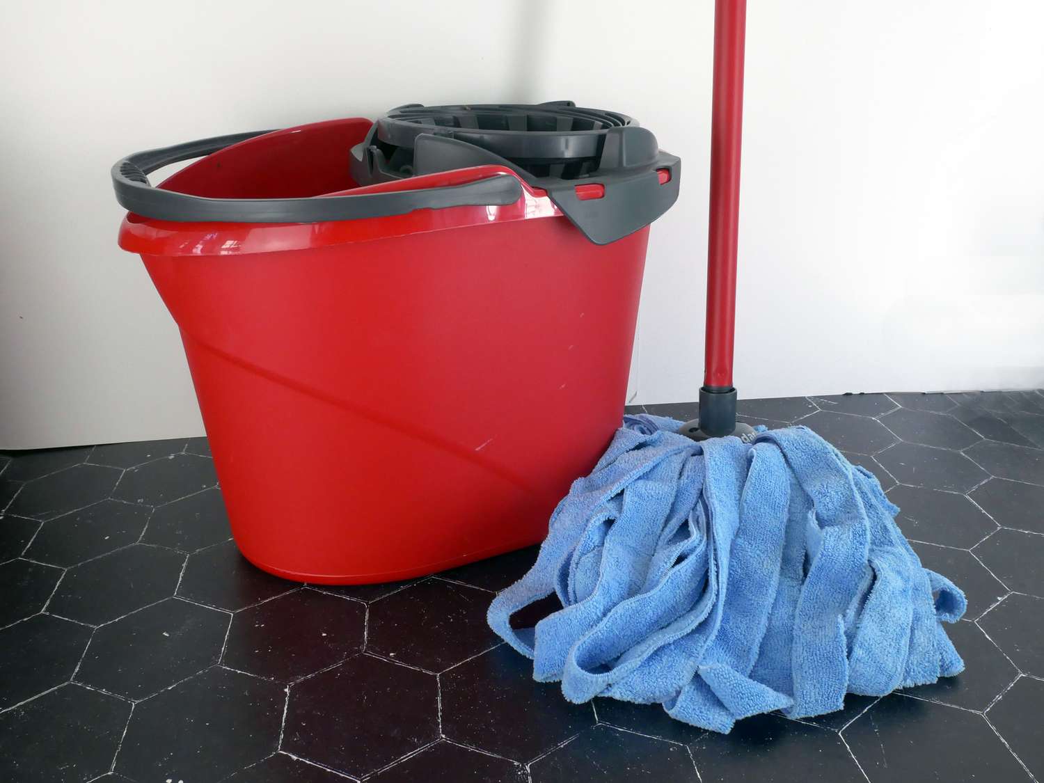 o cedar mop with blue mop head on black tile surface