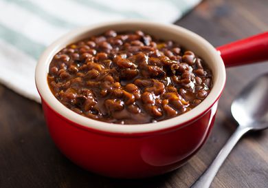 Red single-serving crock with slow-cooked baked beans.