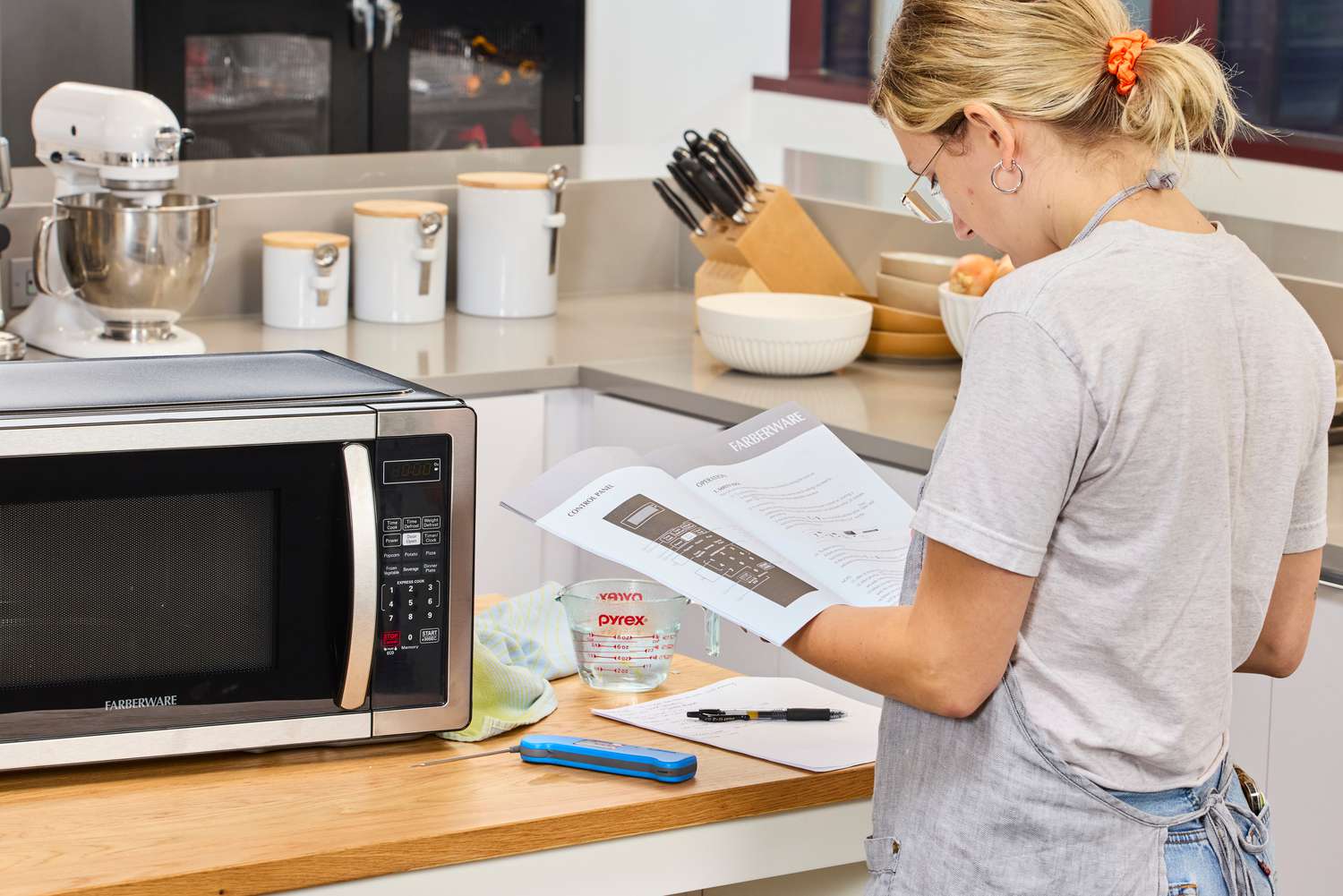 A person reading the instruction manual for the Farberware Countertop Compact Microwave (FMWO11AHTBKB) 