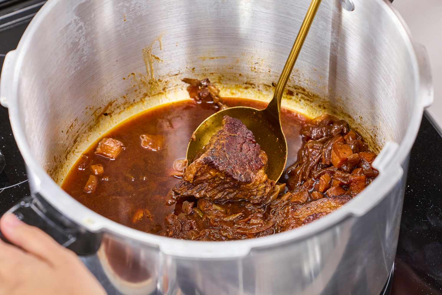 Meat cooked in the Presto 16-Quart Pressure Canner and Cooker is stirred with a ladle