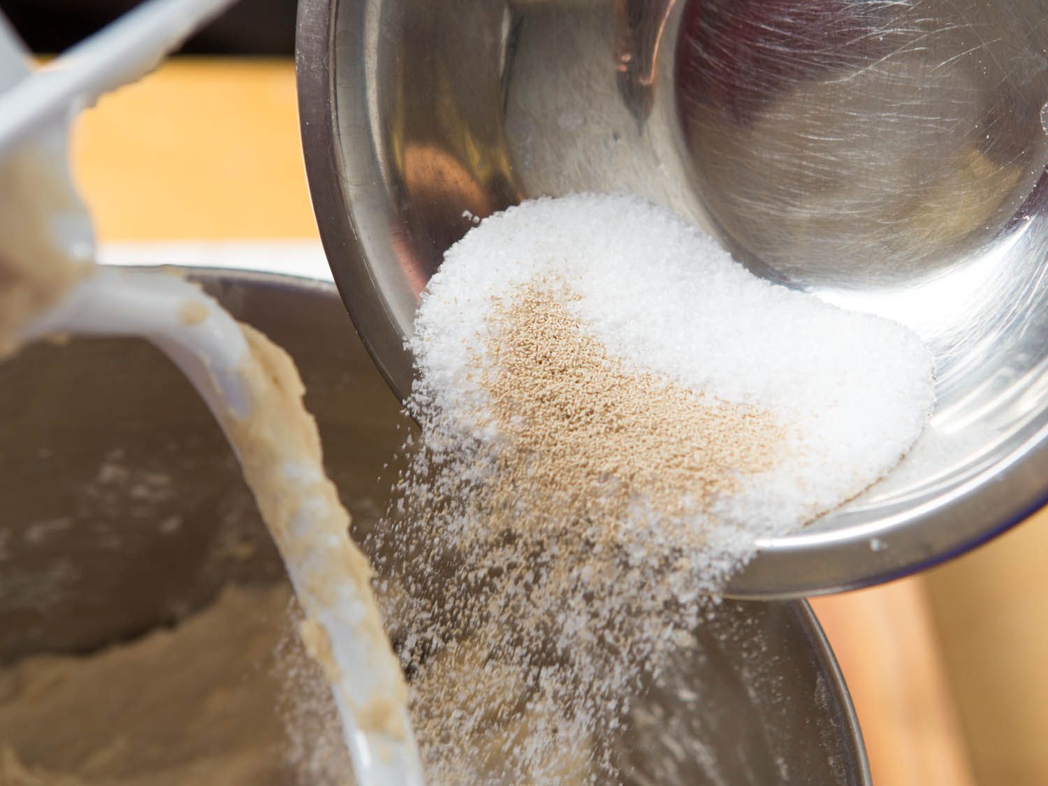 Salt and yeast being poured and mixed into the dough mixture.