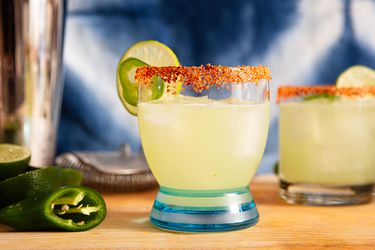 A spicy margarita cocktail garnished with a tajin rim and lime