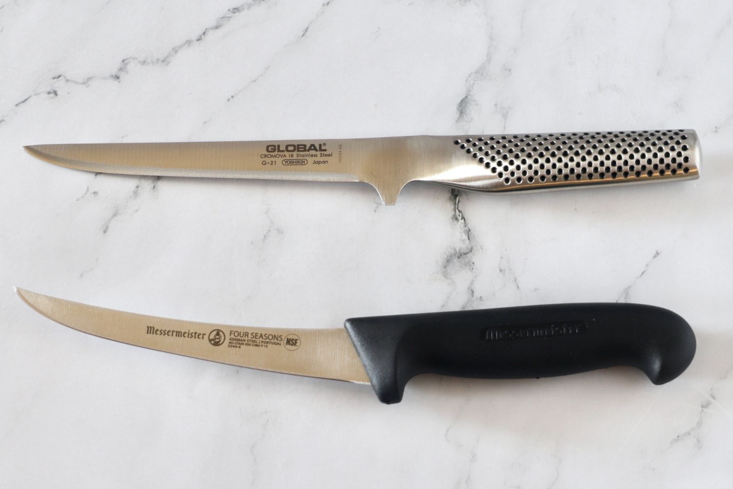 Two boning knives side by side on a counter