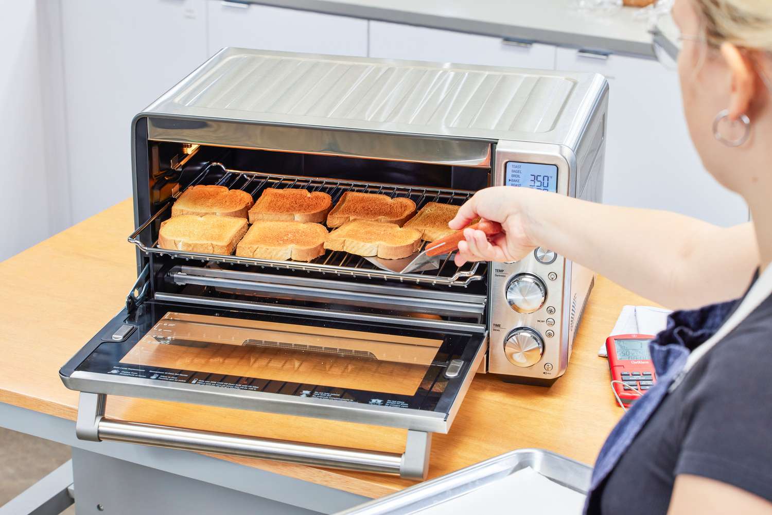 A person removing toast from the Breville the Smart Oven Air Fryer
