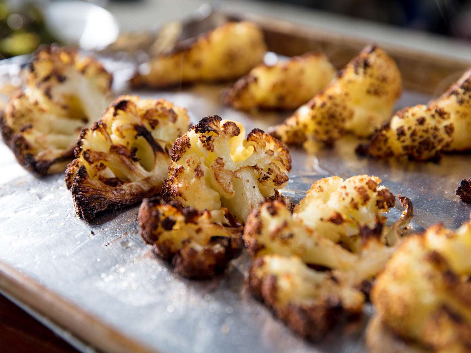 Charred cauliflower florets on a foil-lined baking sheet.