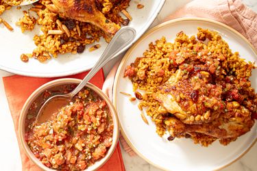 Plates of cooked chicken served with seasoned rice and a bowl of sauce on the side