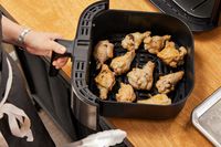 Wings in the Instant Vortex Plus 6QT XL Air Fryer basket on a wooden surface