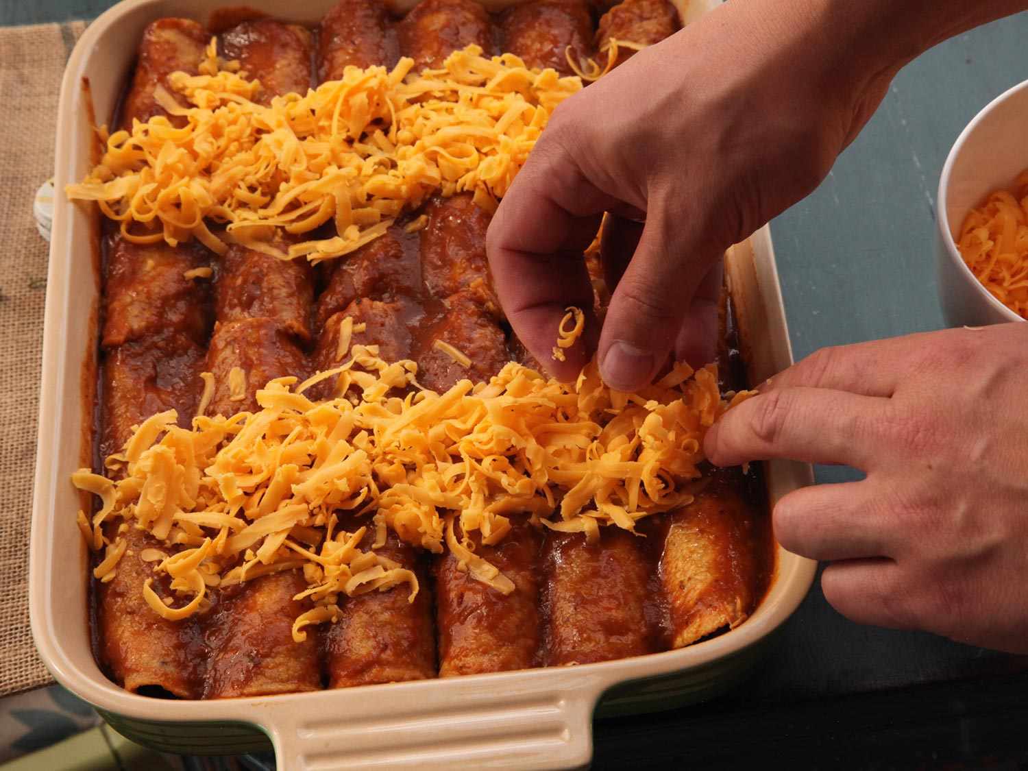 Cheese is piled down the center of each row of enchiladas.