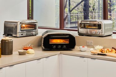 Three indoor pizza ovens on a kitchen countertop.