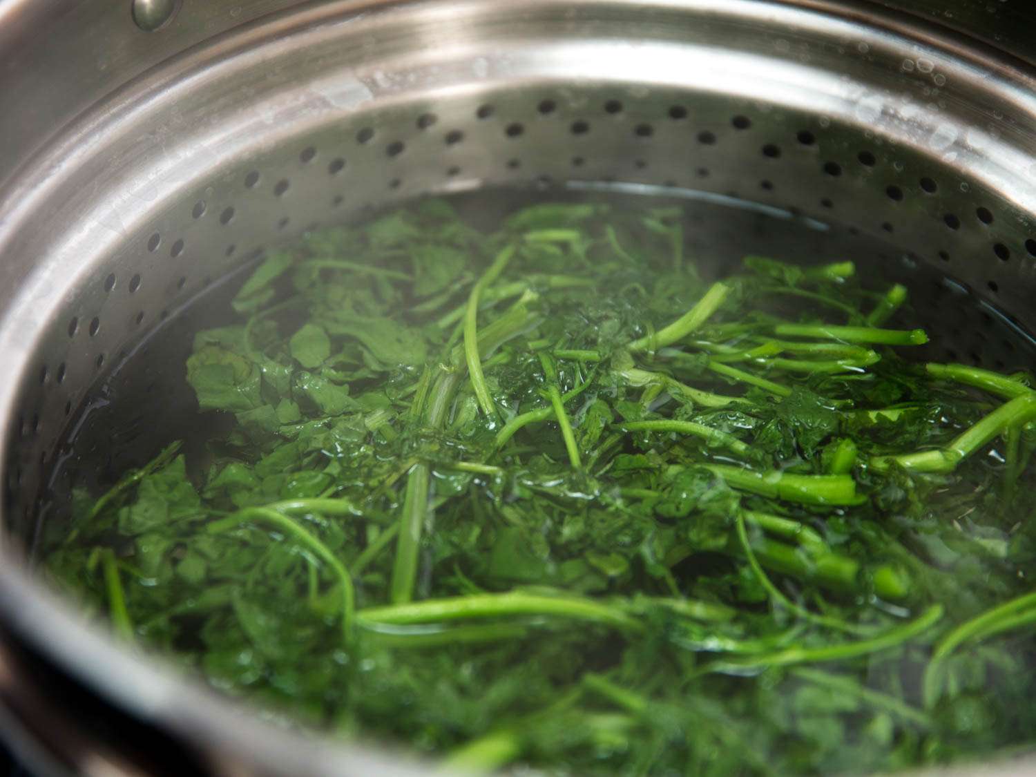 Spinach blanching in a pot of boiling water.