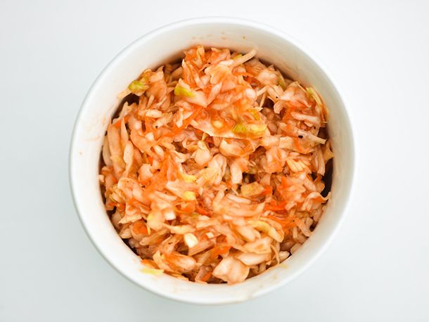 Closeup of red coleslaw in a white bowl on a white background.
