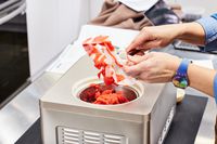 A person using a spatula to remove sorbet from the mixer of the Whynter 2-Quart Ice Cream Maker