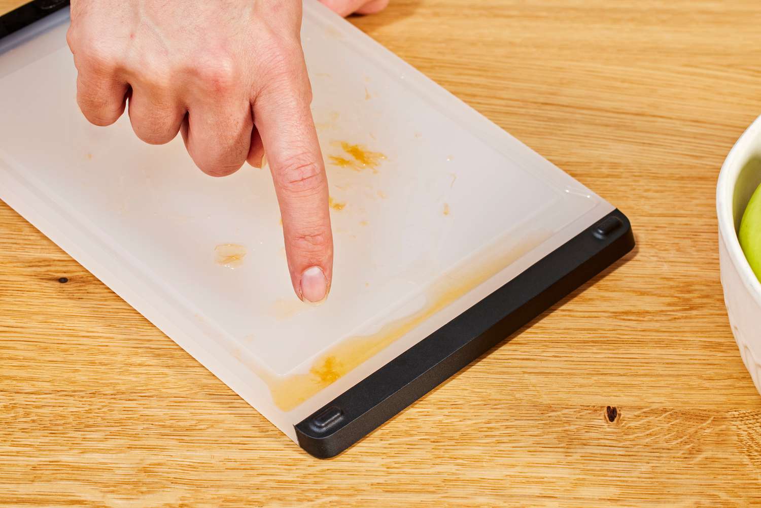 A person pointing out the juice well on an OXO cutting board.