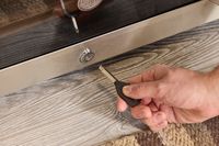 A hand holding a key unlocking a wine fridge.