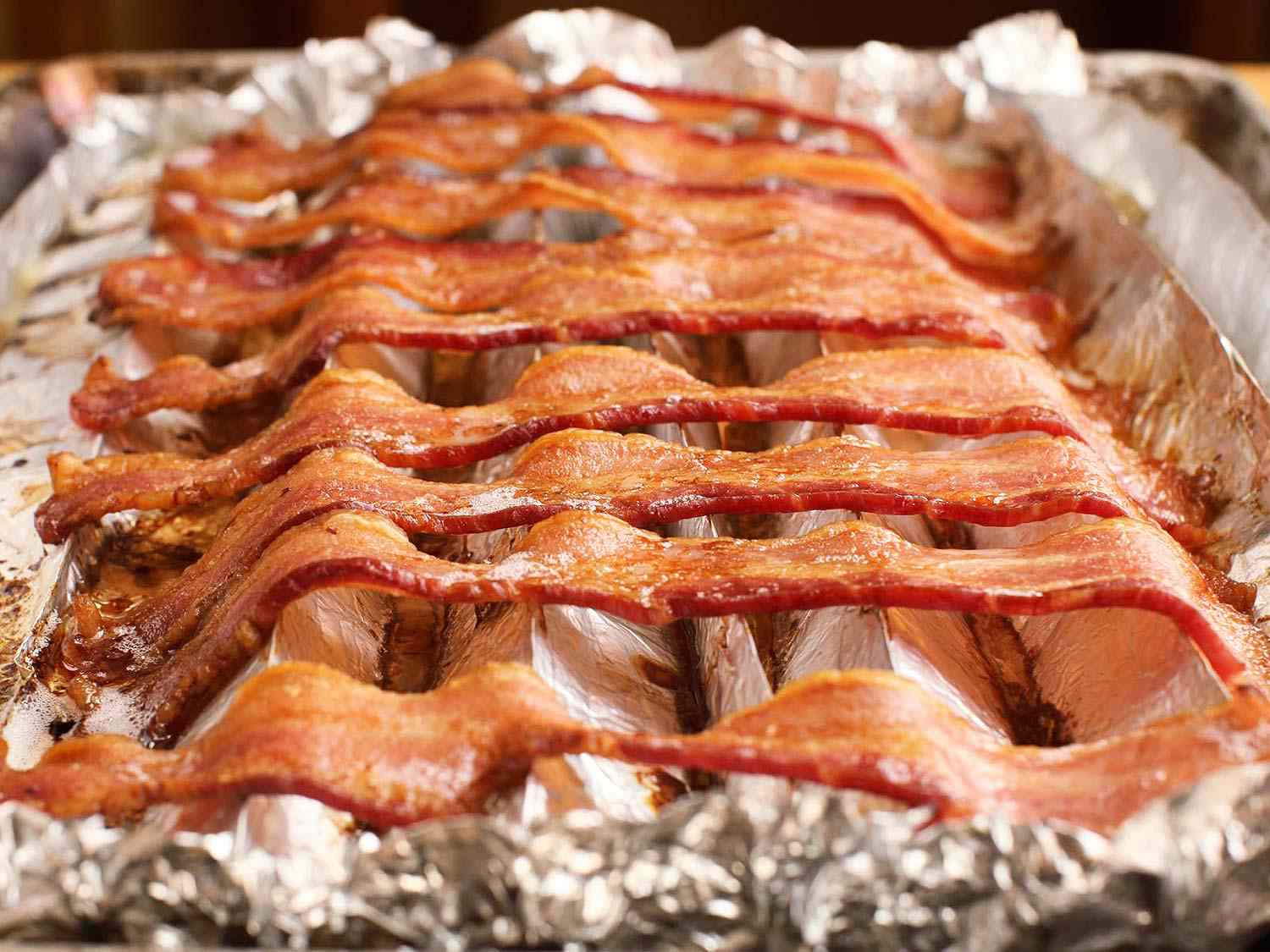 Close-up of bacon baked on crimped foil.
