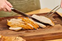 A person carving a Grassland Beef Pasture Raised Turkey on a cutting board