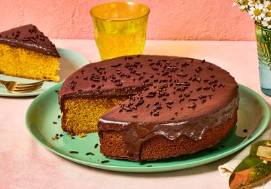 Brazilian carrot cake topped with chocolate glaze, a slice is served nearby