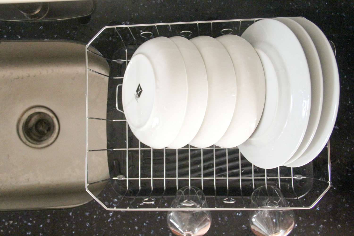 The Rubbermaid dish rack drying plates and bowls next to a kitchen sink.