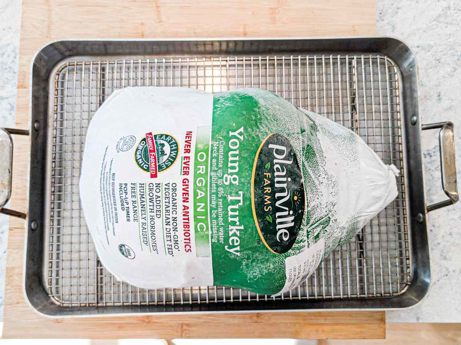 A packaged frozen turkey placed on a large roasting pan rack
