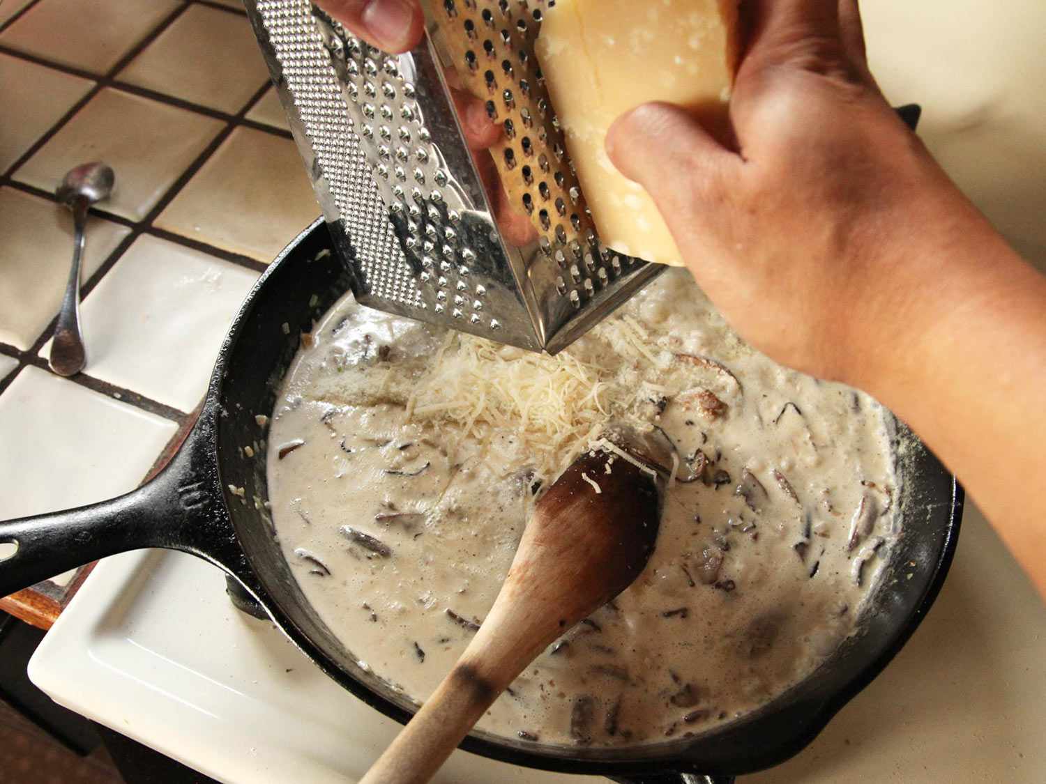 Grating parmesan cheese into the sauce.