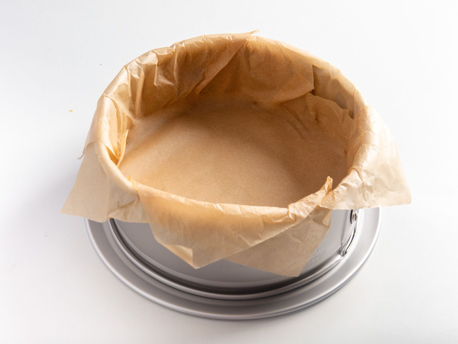Parchment paper lining the inside of a springform cake pan.