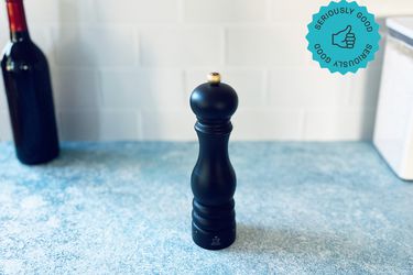 the peugeot pepper mill on a blue surface with white tile backdrop