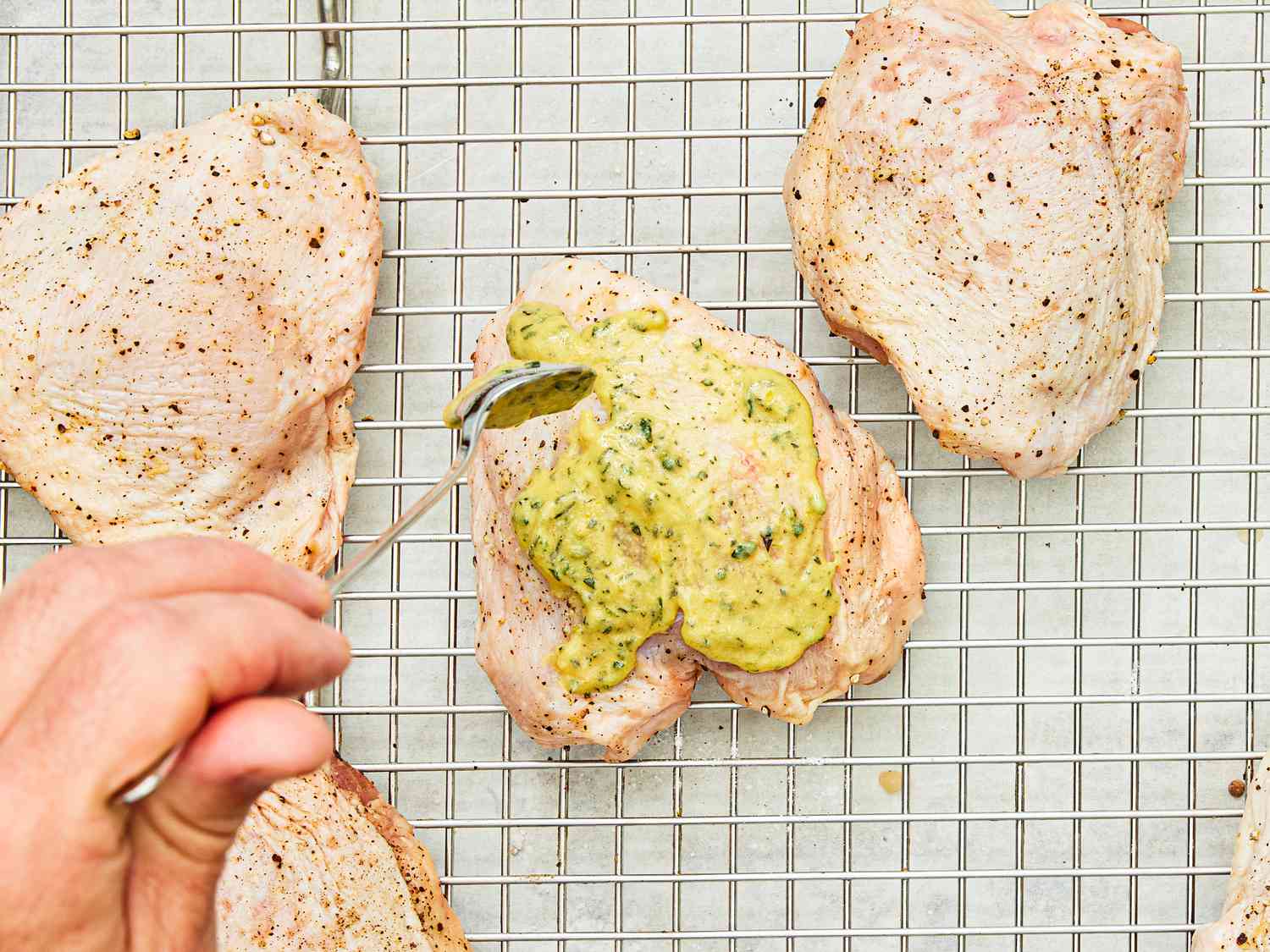 Putting a spice blend onto raw brined chicken thighs