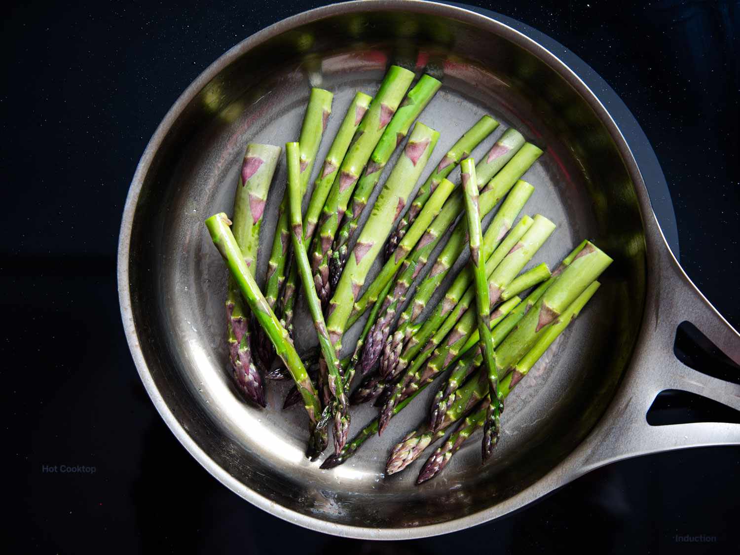 Trimmed, raw asparagus in a bare carbon steel skillet.