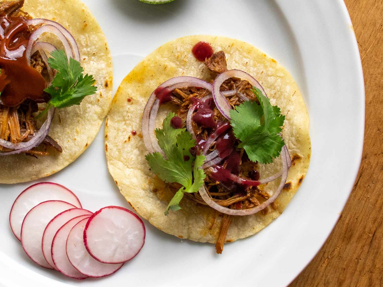Overhead of pork tacos drizzled with berry habanero hot sauce.