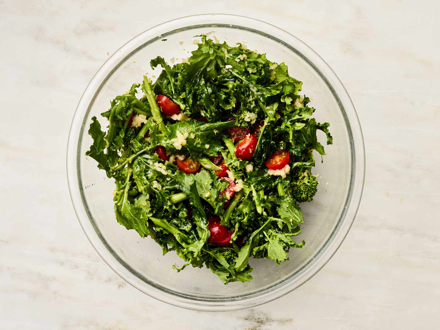 A glass bowl containing mixed greens with cherry tomatoes and grated cheese