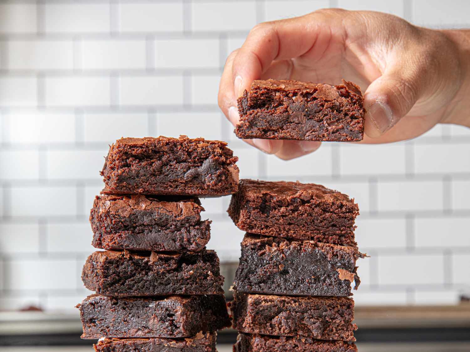 A stack of brownies with one being held above the stack