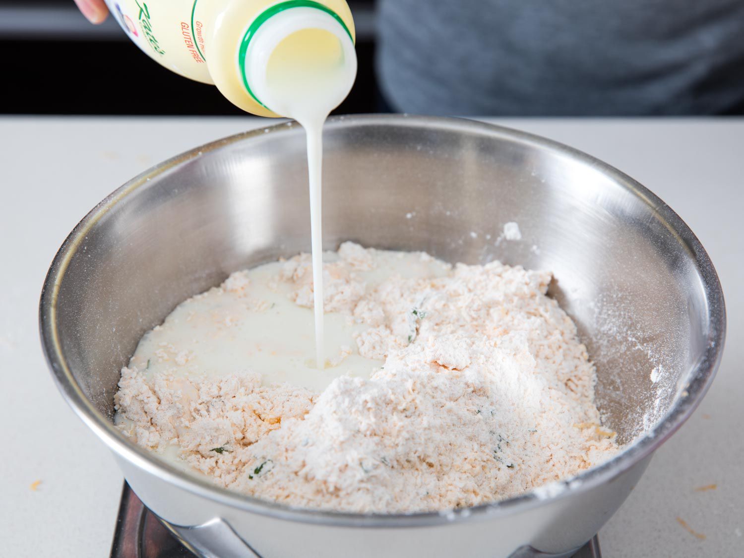 Cultured buttermilk is poured into a bowl to make the dough for cheddar bay biscuits.