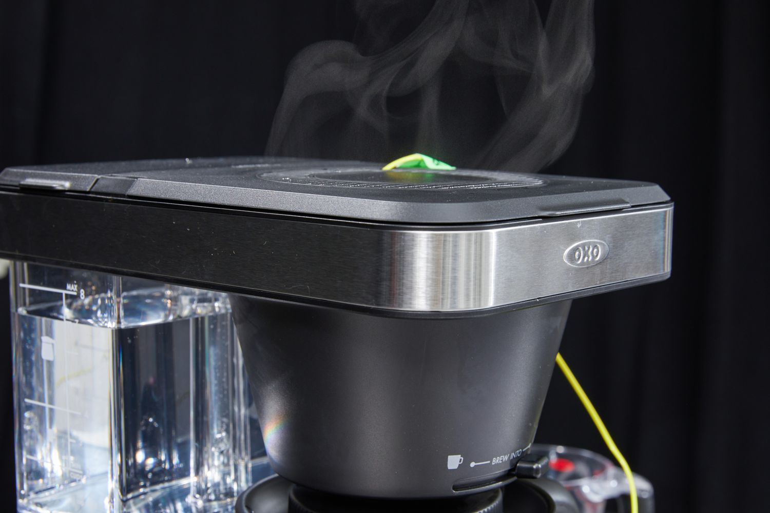 An OXO Brew 8cup coffee maker with steam rising from the top showing the brewing process