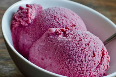 Closeup of two scoops of roasted plum, ginger, and honey ice cream, served in a small bowl.