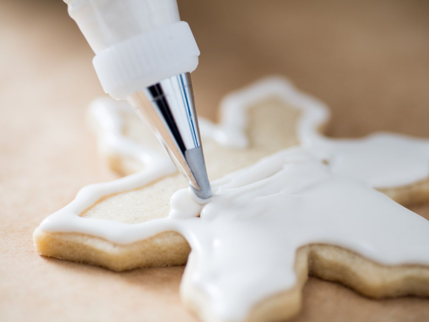 Royal icing is piped onto a rolled sugar cookie.