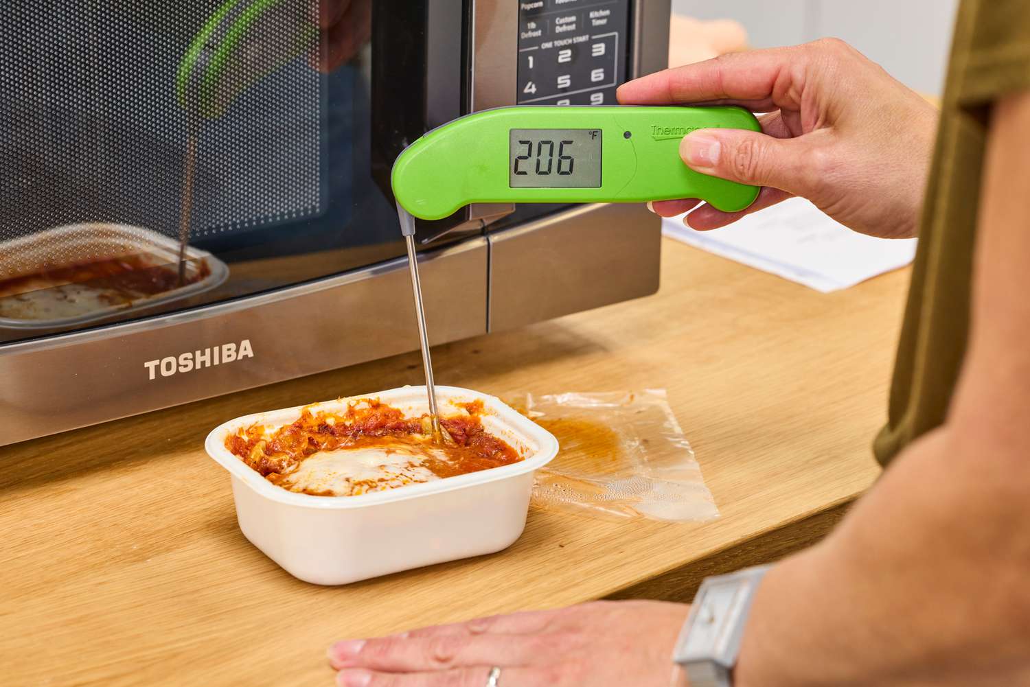 A person holding a thermometer to food made in the Toshiba EM131A5C-BS Microwave Oven