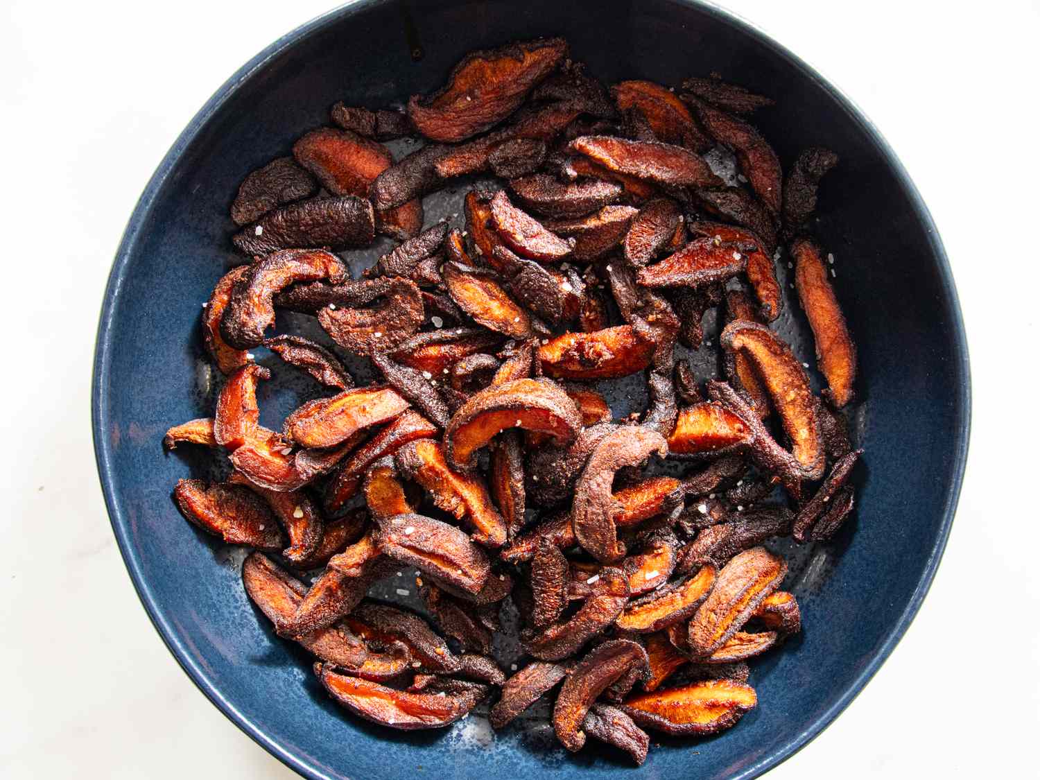 A bowl containing roasted mushrooms sliced and cooked until browned