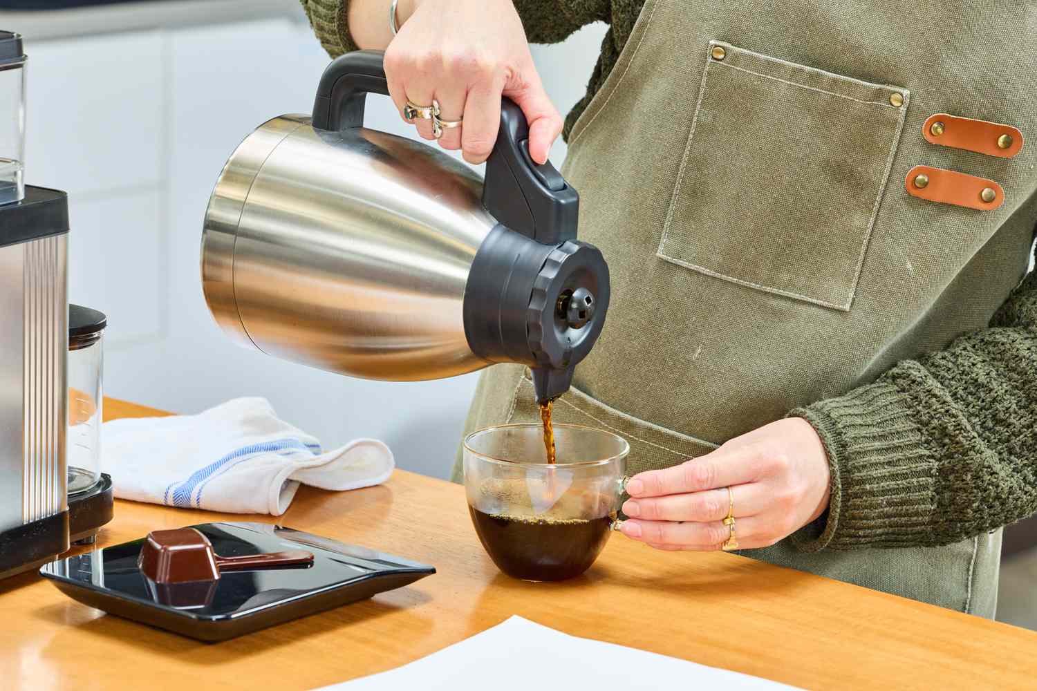 A person pours coffee from the Technivorm Moccamaster carafe into a mug.