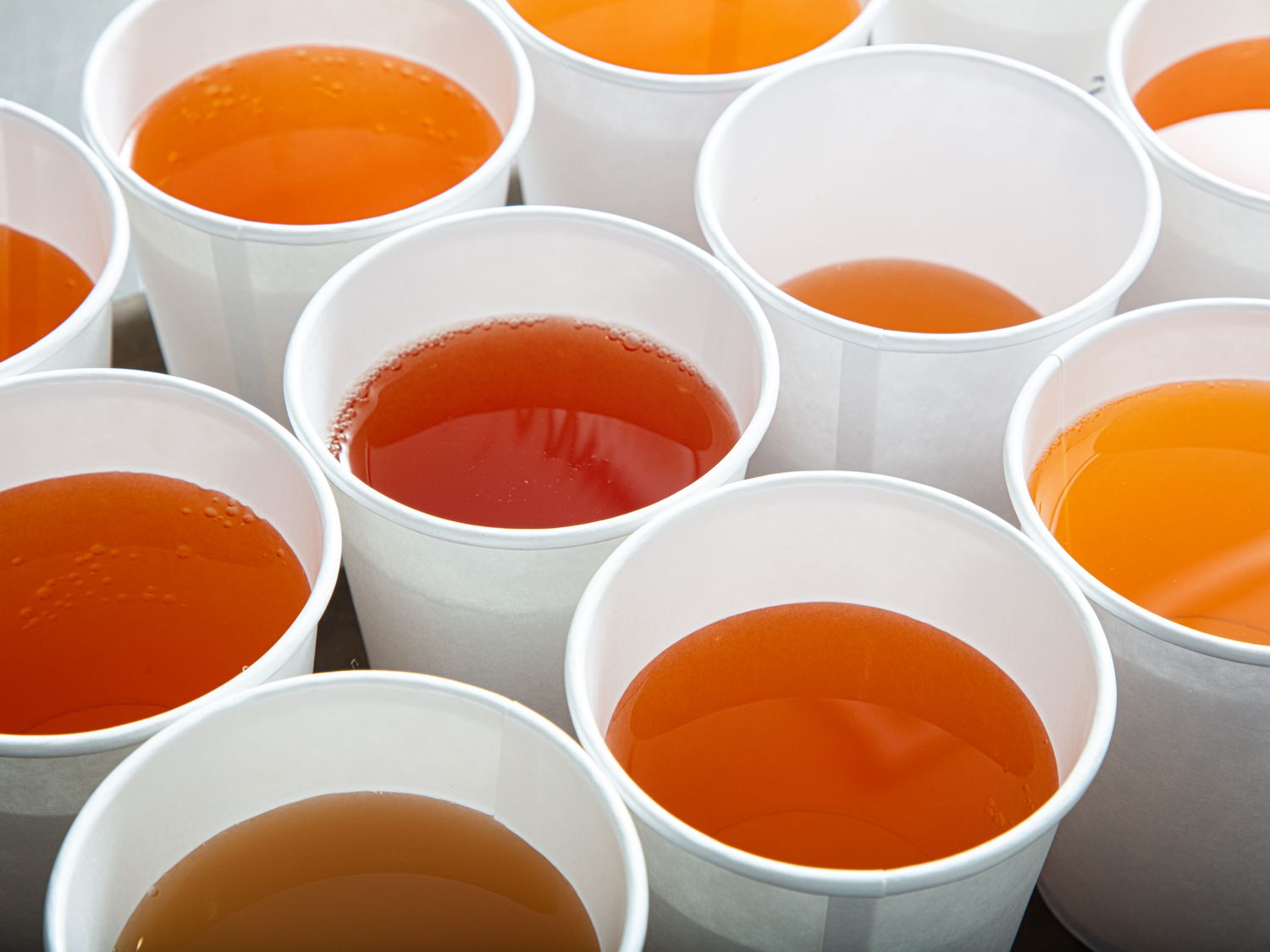 Multiple cups of apple juice arranged in rows